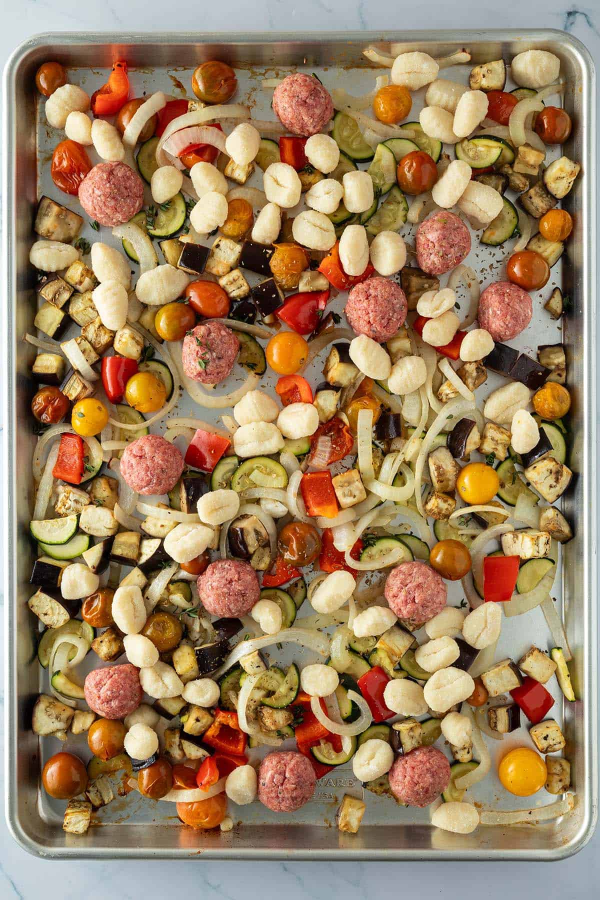 Gnocchi und rohe Hackb&auml;llchen wurden zu dem vorger&ouml;steten Gem&uuml;se auf das Blech gegeben.