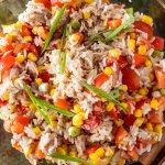 Nahaufnahme von einer Sch&uuml;ssel Reissalat mit Thunfisch, Tomaten, Mais, Paprika und Fr&uuml;hlingszwiebeln.