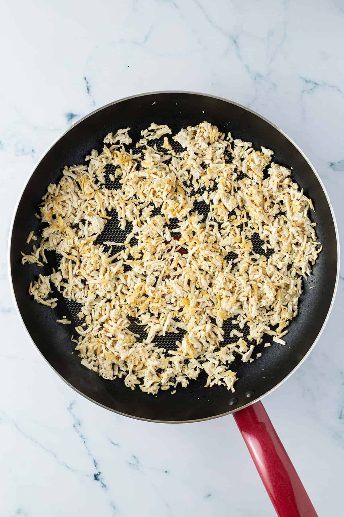 Geraspelter Tofu wird in einer Pfanne angebraten.