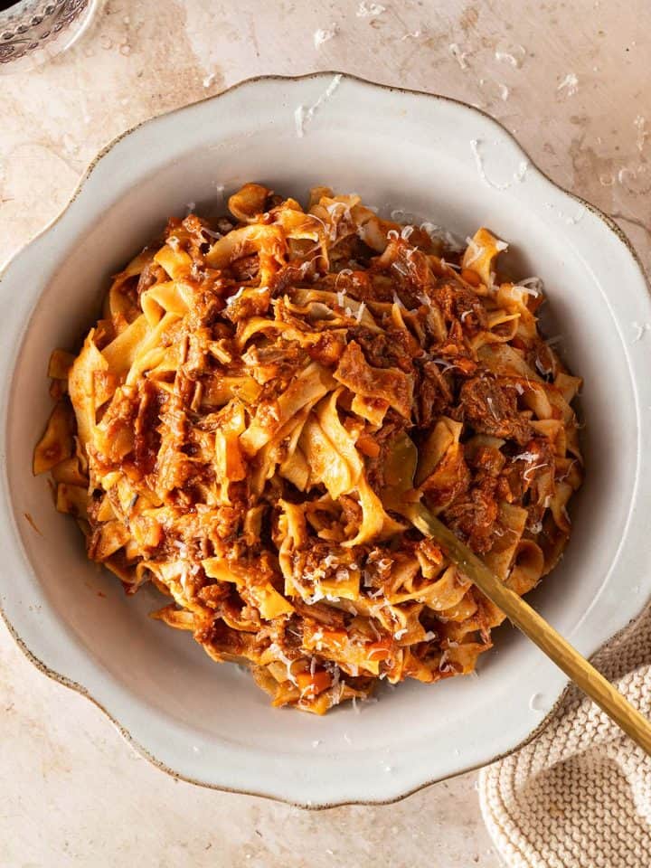 Selbstgemachte Bandnudeln mit italienischem Rinderragout und frisch geriebenem Parmesan in einem tiefen Teller.