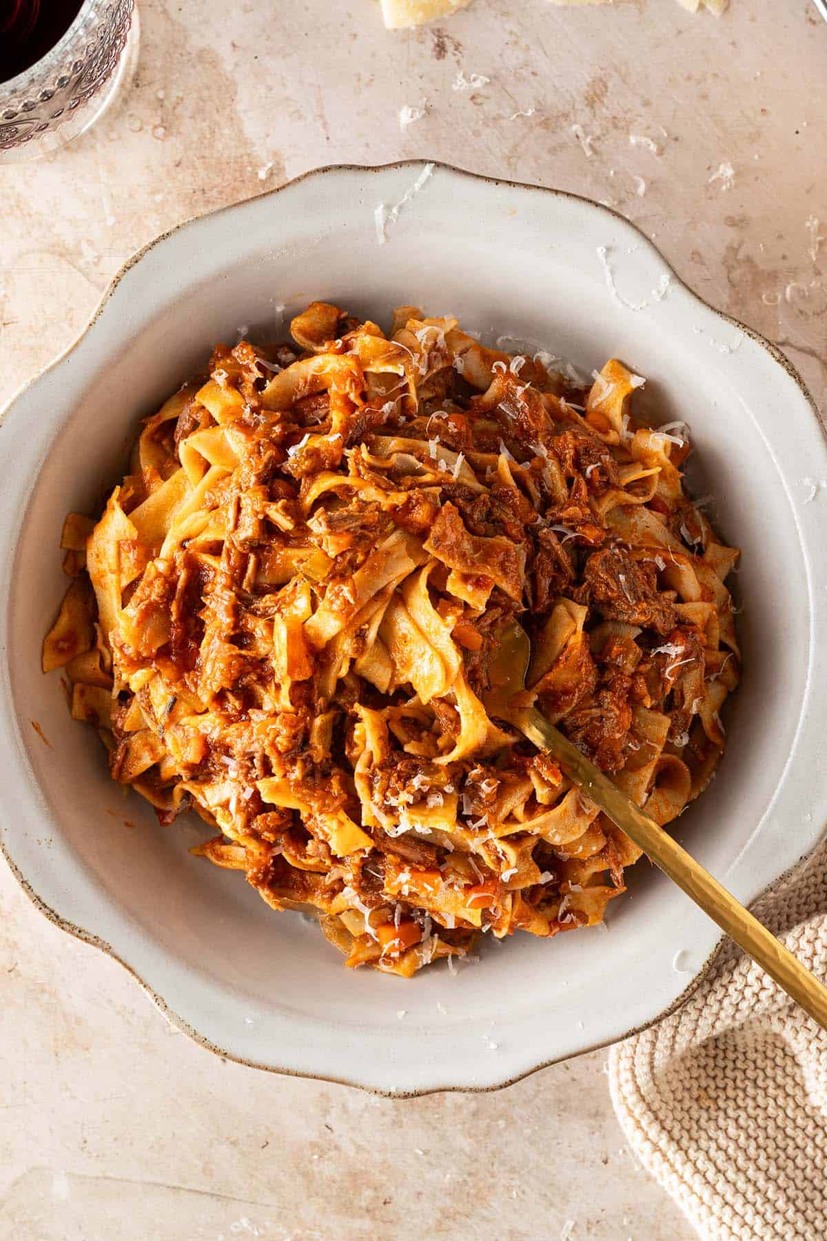 Selbstgemachte Bandnudeln mit italienischem Rinderragout und frisch geriebenem Parmesan in einem tiefen Teller.