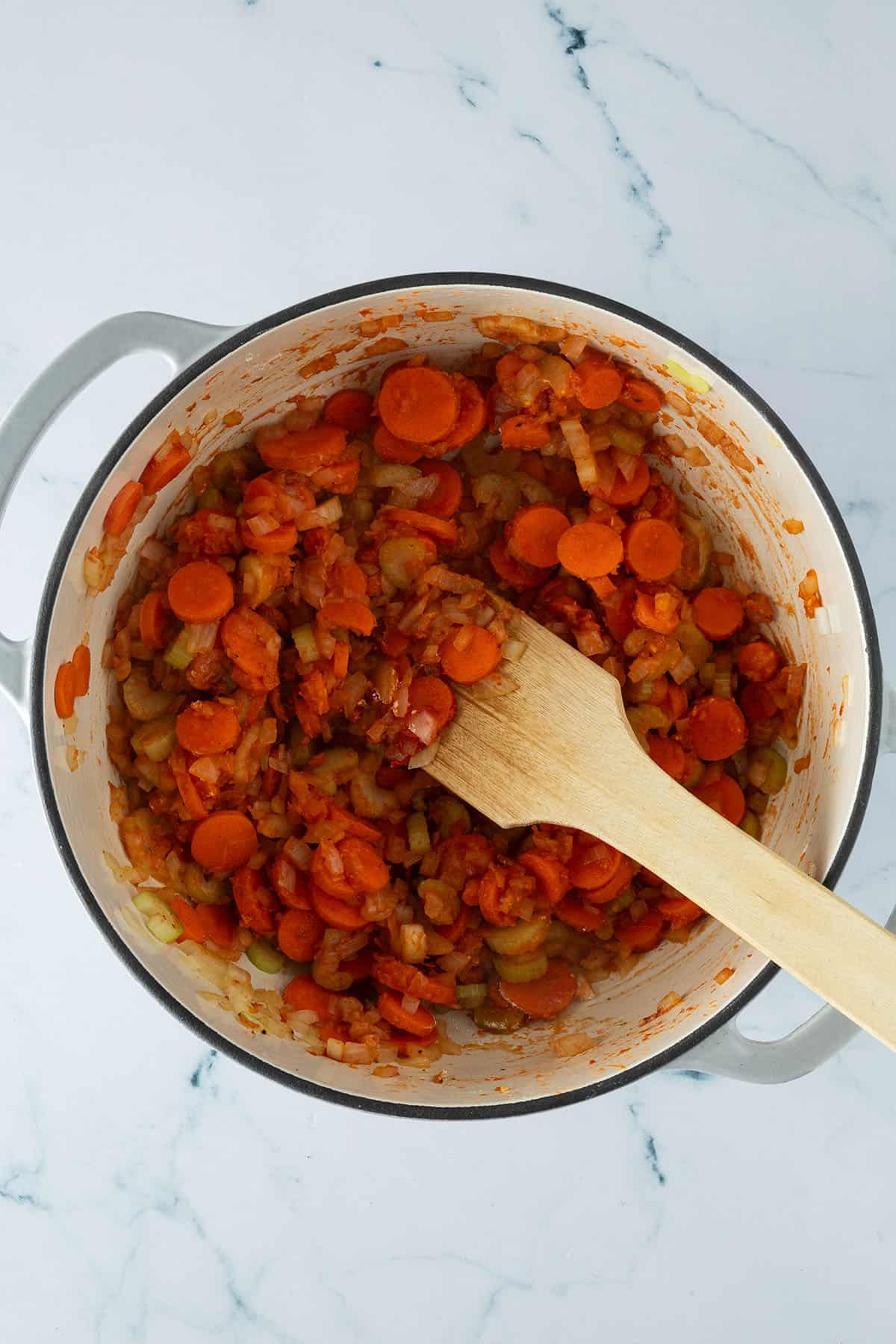 Angeschwitzte Karotten, Sellerie und Zwiebeln im Topf, mit Tomatenmark und Mehl.