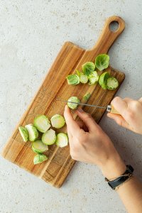 Rosenkohl K&ouml;pfchen wird mit einem Messer halbiert.