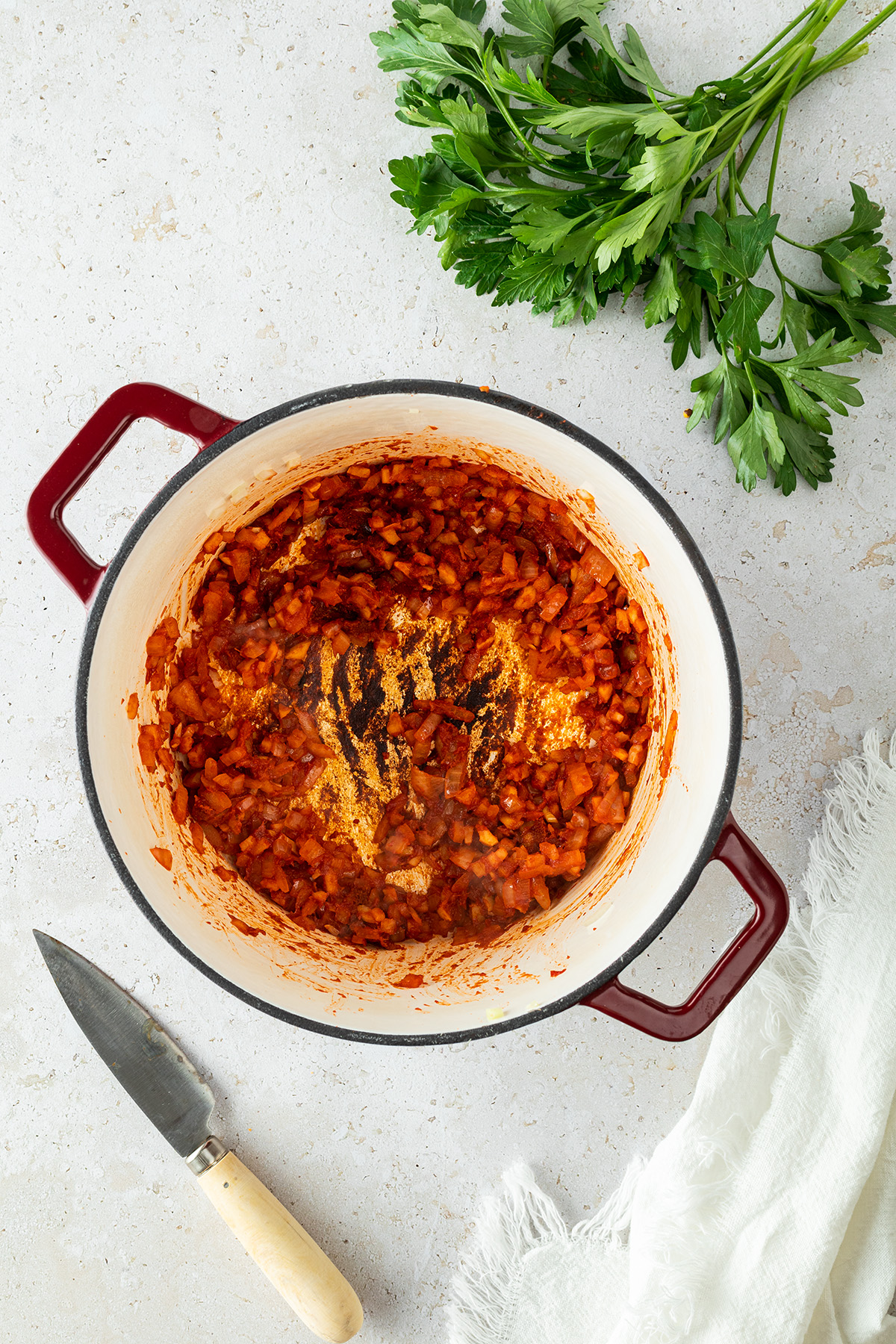 Eine Mischung aus Zwiebeln, Knoblauch, Ingwer, Tomatenmark und Chilipaste in einem Topf.