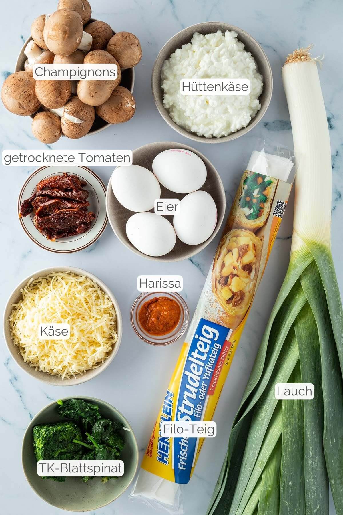 Foto aller Zutaten mit jeweiligen Textbeschriftungen, die f&uuml;r eine schnelle Gem&uuml;se-Quiche ben&ouml;tigt werden.