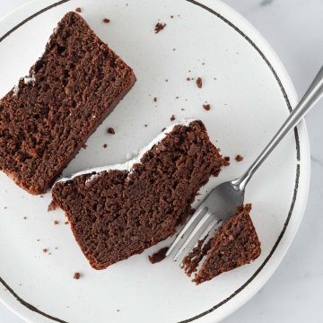 Zwei St&uuml;cke saftiger Schokokuchen ohne Mehl auf einem Teller mit einer Gabel.