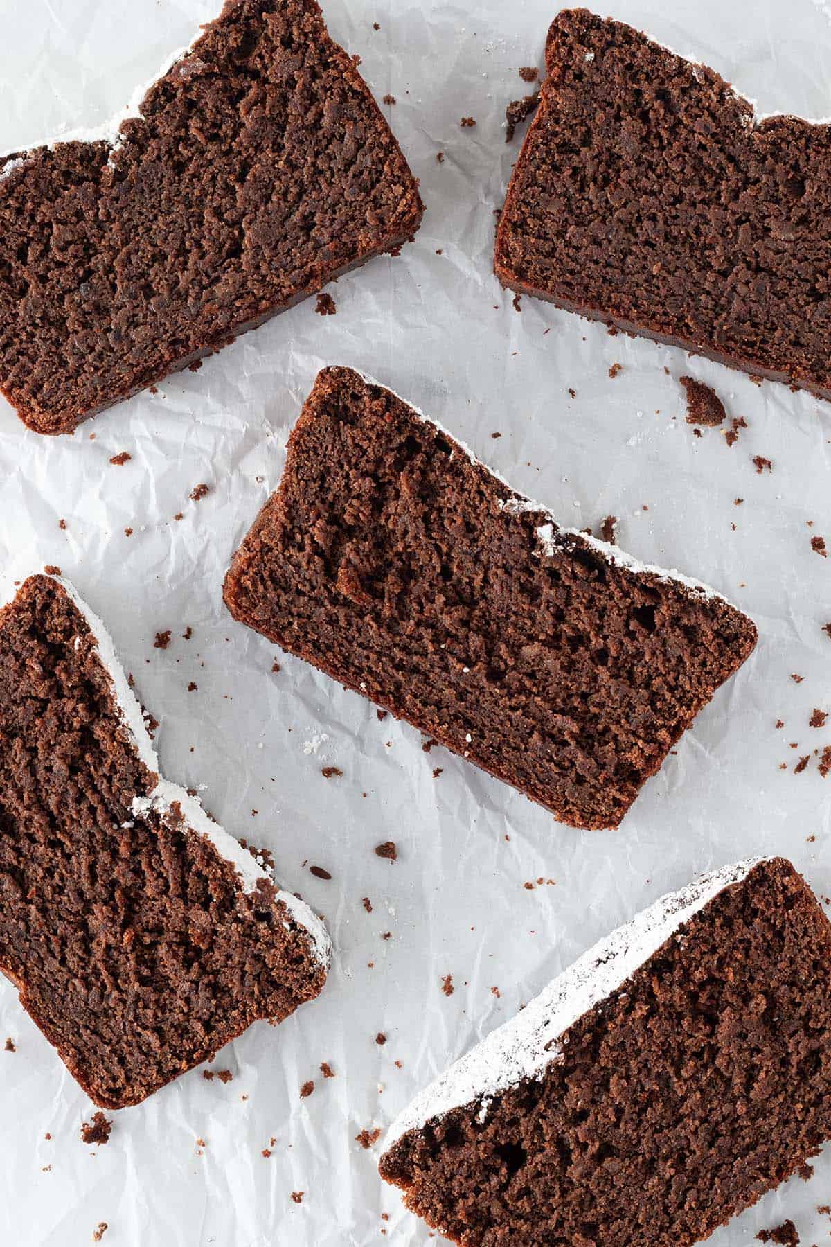Mehrere St&uuml;cke saftigen Schokokuchen ohne Mehl auf wei&szlig;em Backpapier.