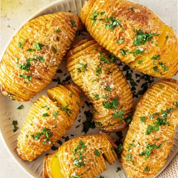 Vogelperspektive auf einen Teller mit knusprigen F&auml;cherkartoffeln, die mit Parmesan &uuml;berbacken wurden.