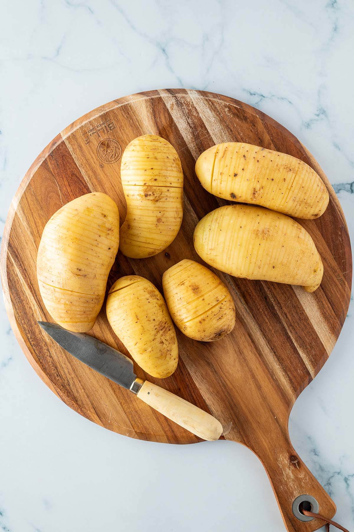 D&uuml;nn eingeschnittene Kartoffeln auf einem Holzbrett.