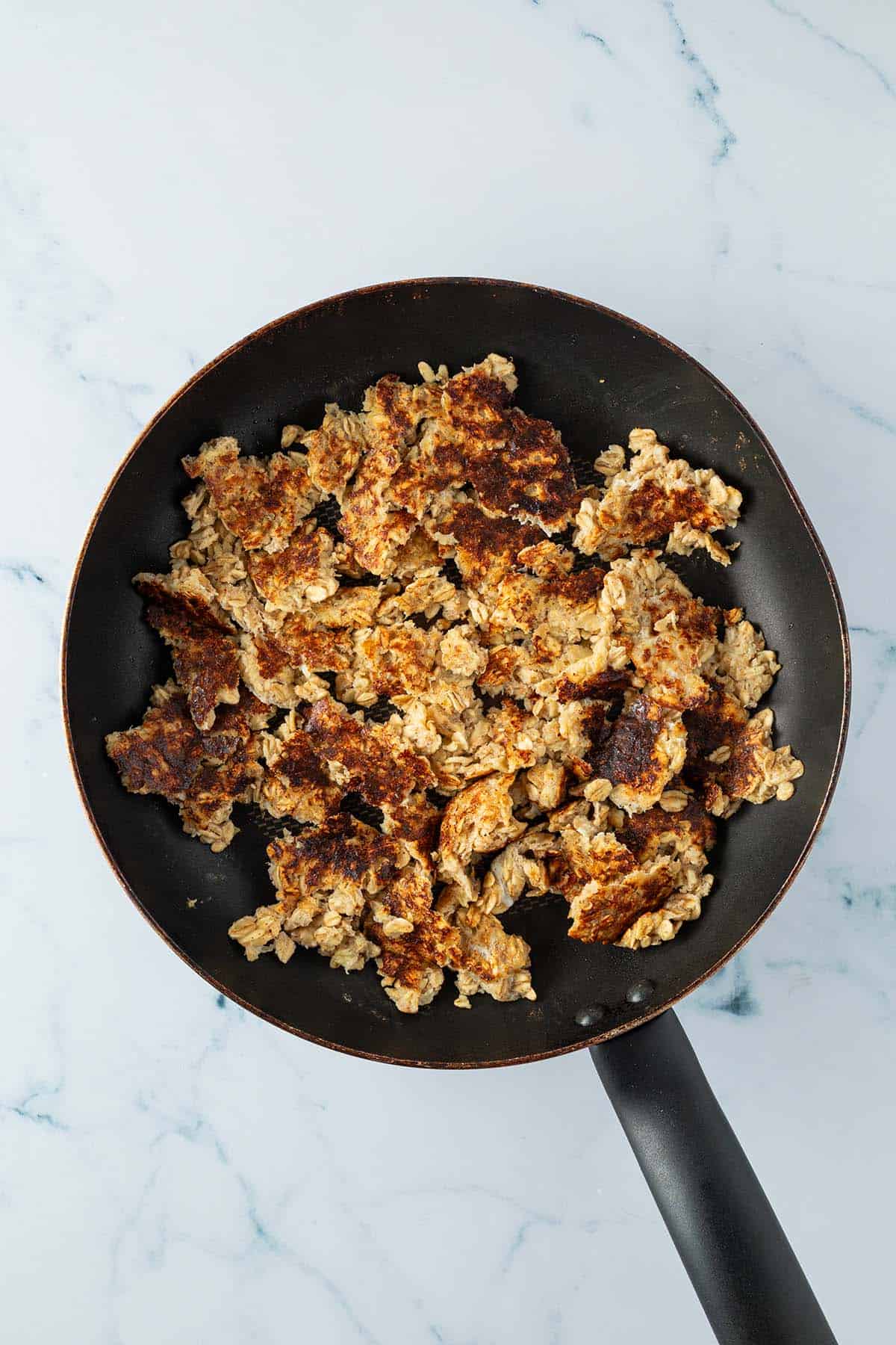 Pfanne mit zerkleinertem Haferflocken-Kaiserschmarrn.