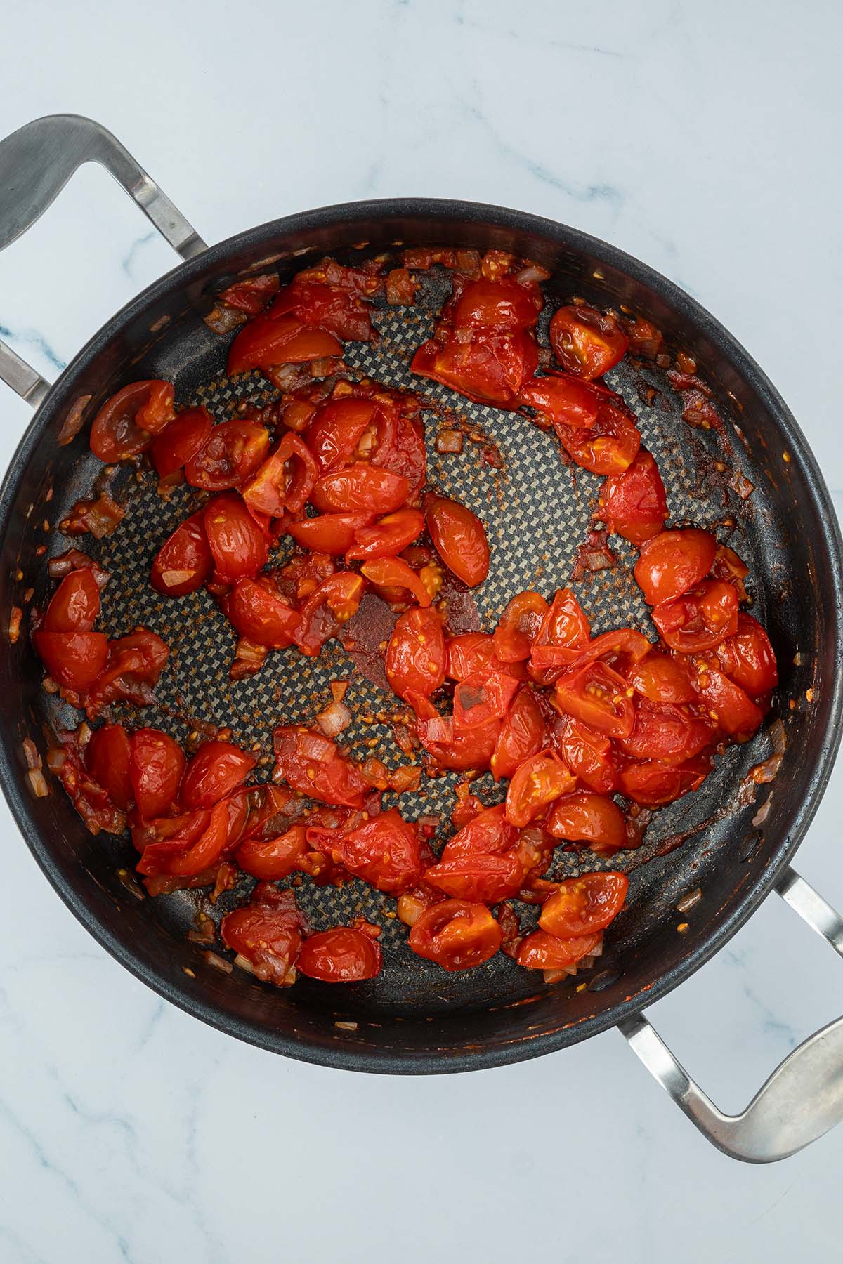 Angebratene Tomaten mit Tomatenmark in einer Pfanne.
