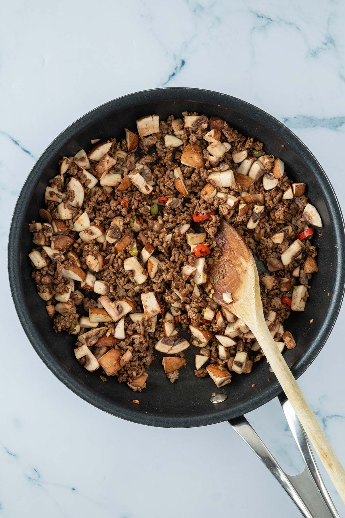 Vogelperspektive auf eine Pfanne mit Hackfleisch und kleingew&uuml;rfelten Champignons.