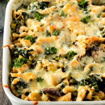 Nahaufnahme eines Spätzleauflaufs mit Käse, Spinat und Gemüse.