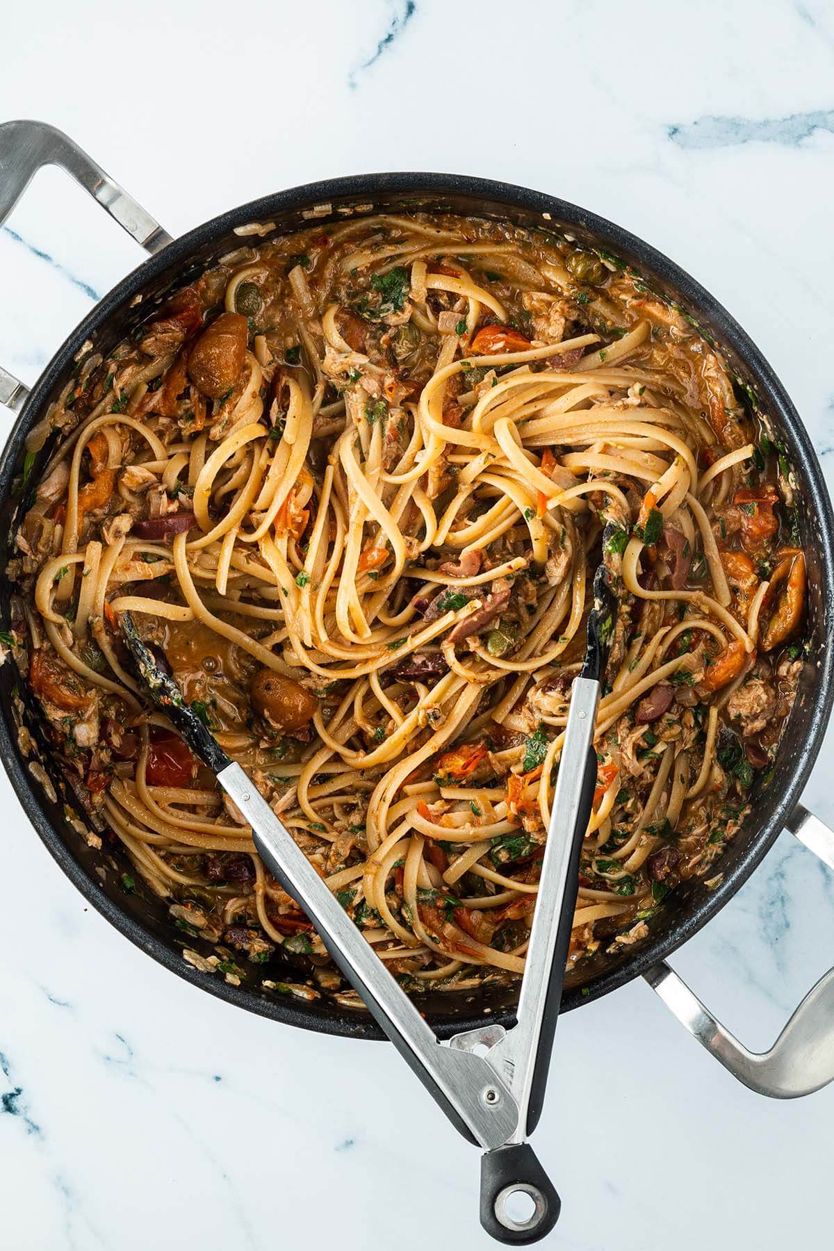 Vogelperspektive mit auf eine Pfanne mit Spaghetti Puttanesca und Thunfisch aus der Dose.