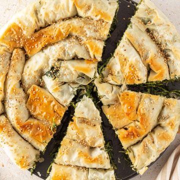 Goldbraun gebackener, griechischer Spinatstrudel, der zur H&auml;lfte angeschnitten ist.