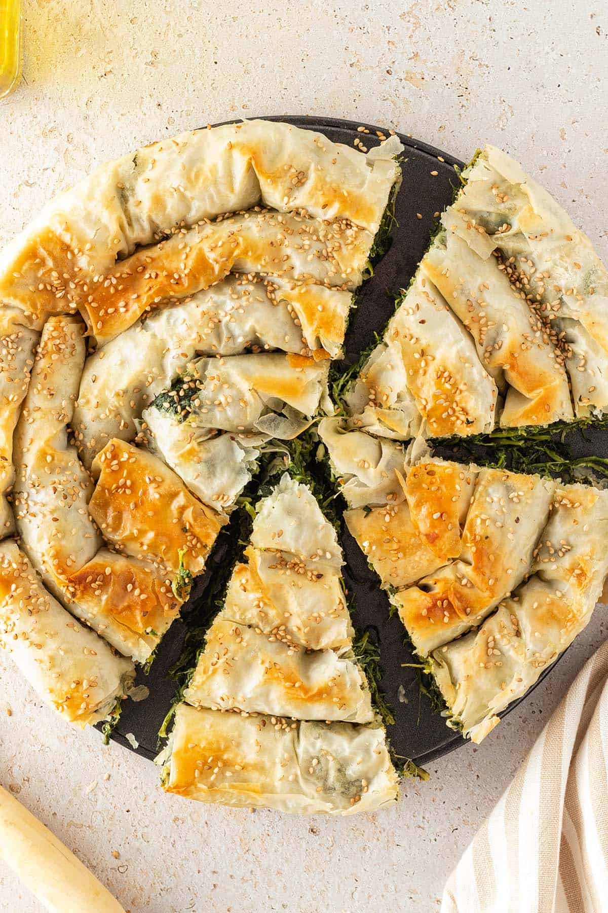 Goldbraun gebackener, griechischer Spinatstrudel, der zur H&auml;lfte angeschnitten ist.