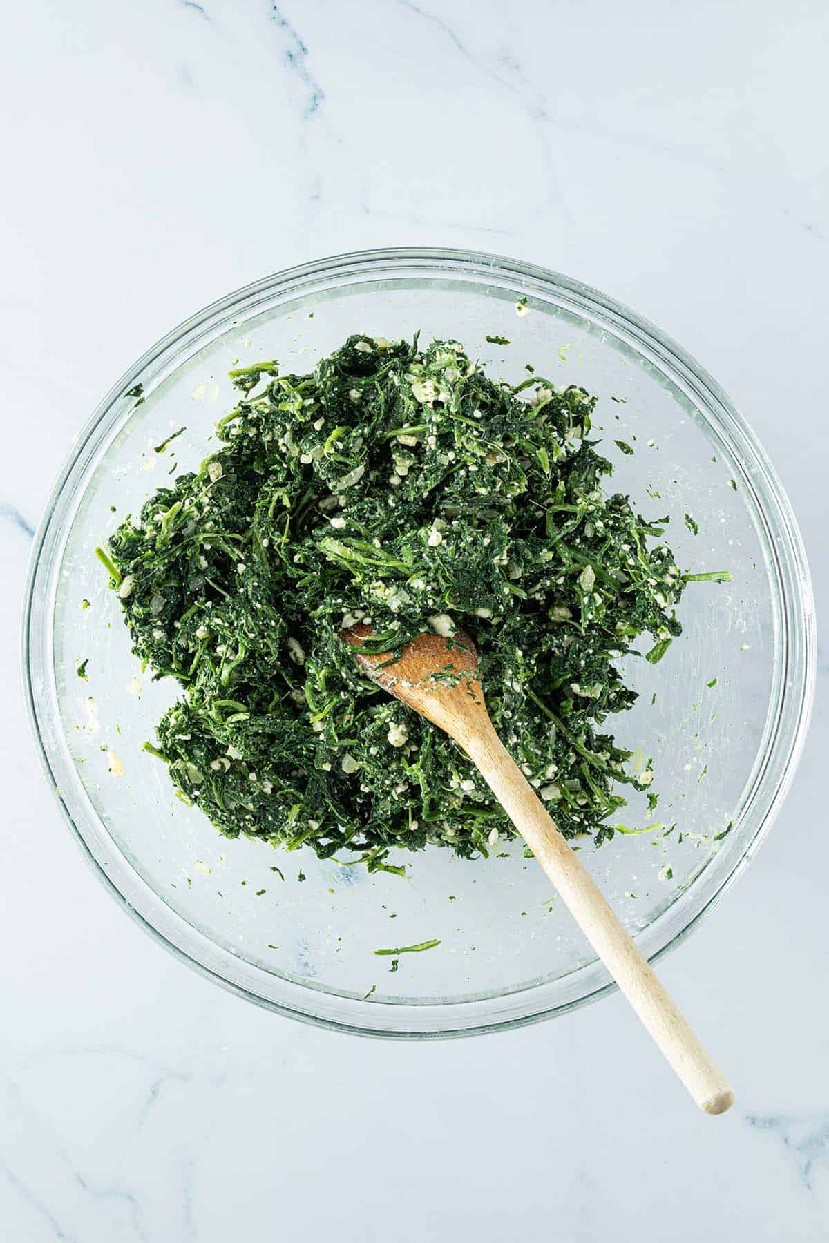 Fertige Spinat-Feta-F&uuml;llung f&uuml;r den griechischen Spinatkuchen in einer Glassch&uuml;ssel.