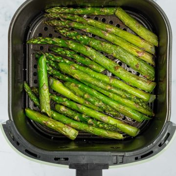 Gr&uuml;ner Spargel in dem Korb einer Hei&szlig;luftfritteuse.