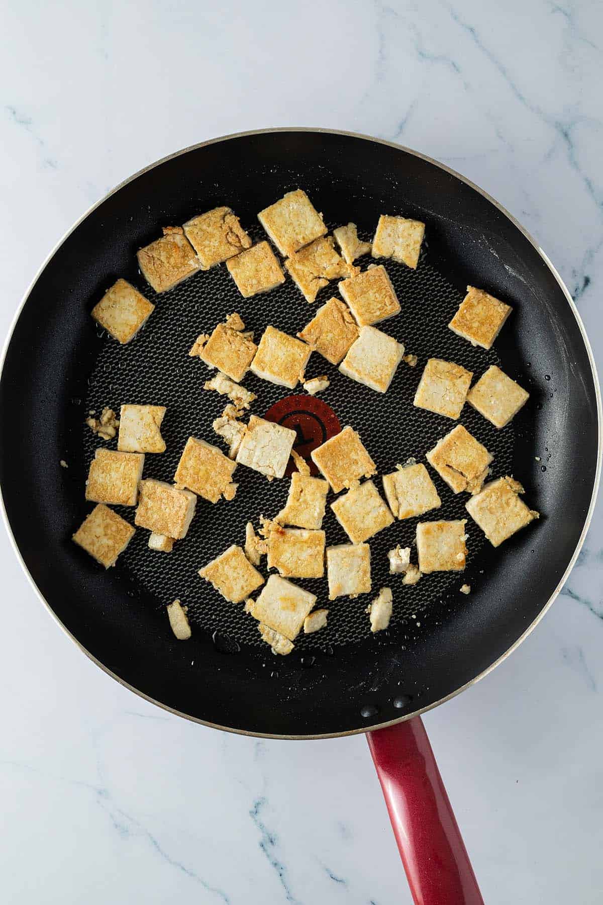 Knusprig angebratene Tofu-Scheiben in einer Pfanne.