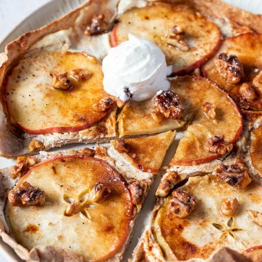 S&uuml;&szlig;er Flammkuchen mit in Scheiben geschnittenen &Auml;pfeln, Ricotta und Waln&uuml;ssen belegt und mit etwas Eis serviert.