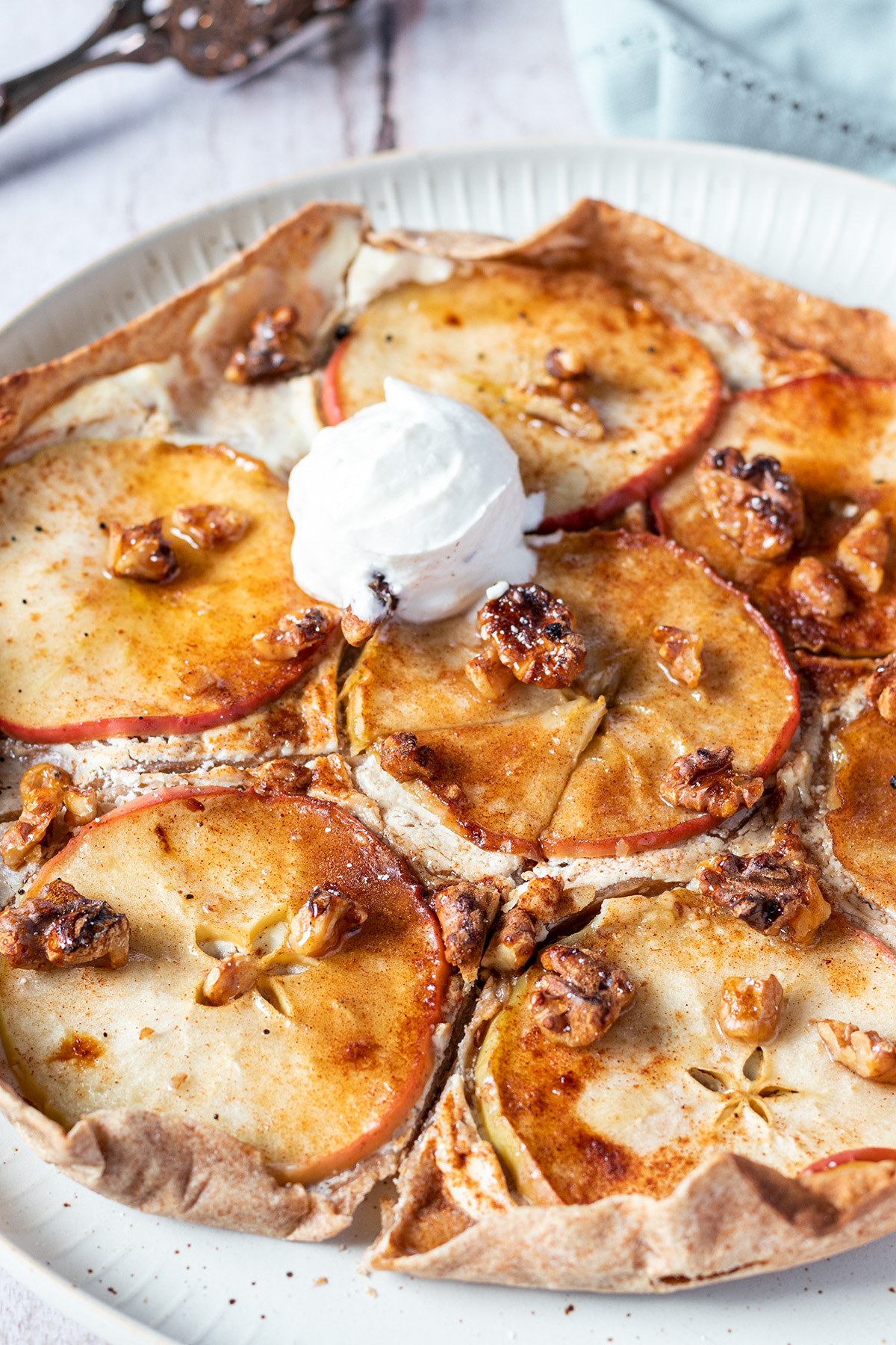 S&uuml;&szlig;er Flammkuchen mit in Scheiben geschnittenen &Auml;pfeln, Ricotta und Waln&uuml;ssen belegt und mit etwas Eis serviert.