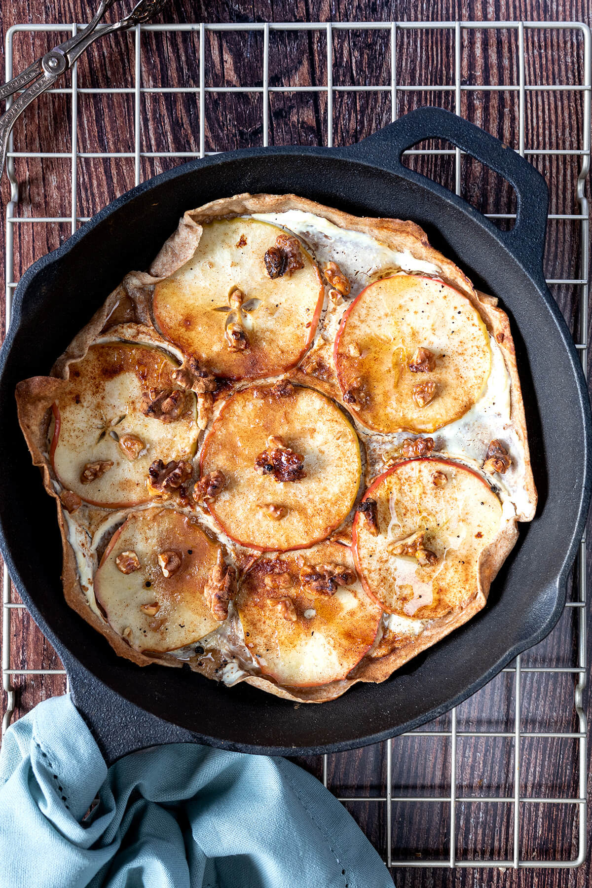 Ein s&uuml;&szlig;er Flammkuchen mit Apfel und Ricotta belegt wurde in einer Gusseisenpfanne im Ofen gebacken.