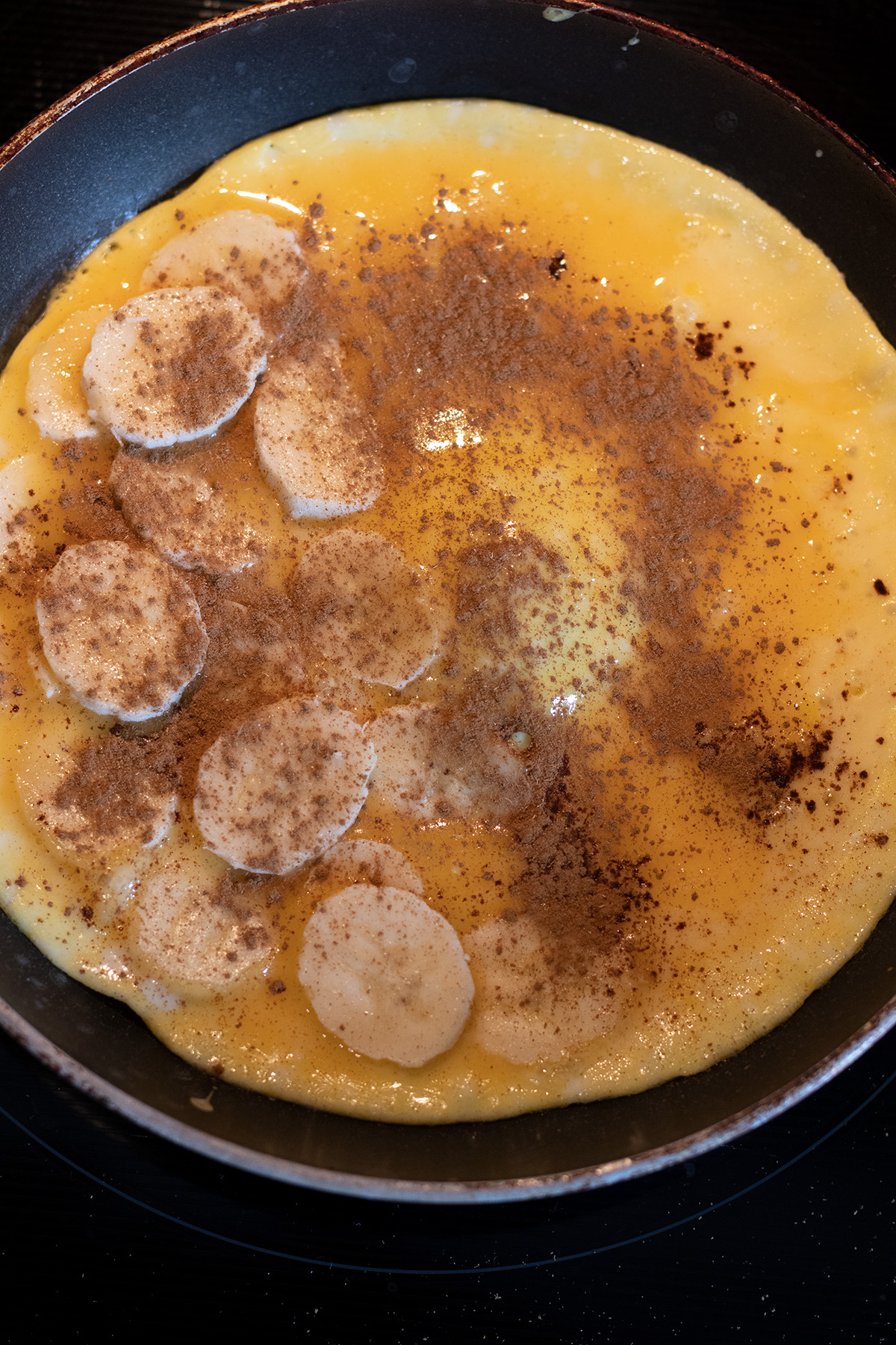 Verquirltes Ei in einer Pfanne mit Bananenscheiben und Zimt.