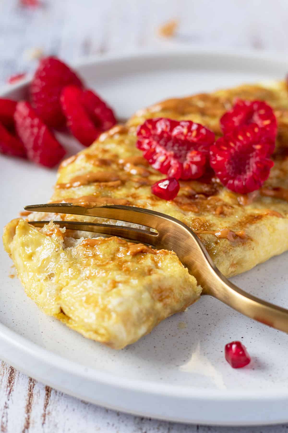 Gabel sticht in ein s&uuml;&szlig;es Omelett mit Fr&uuml;chten.