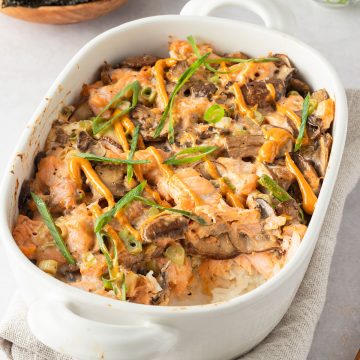 Sushi Auflauf in einer Auflaufform, Nori-Bl&auml;tter und Fr&uuml;hlingszwiebeln im Hintergrund.