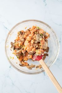 Mischung aus gebratenen Pilzen, Frischk&auml;se und rohen Lachs in einer Glassch&uuml;ssel.