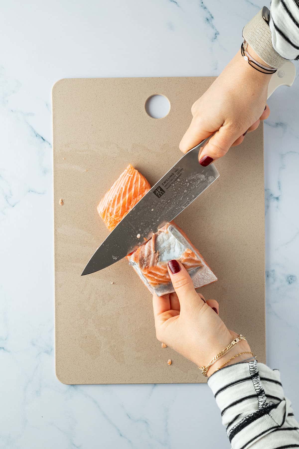 Haut wird mit einem scharfen K&uuml;chenmesser vom Lachs abgetrennt.