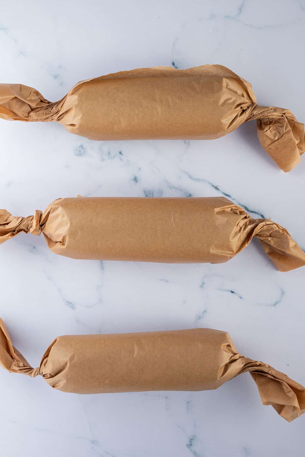 Drei in Backpapier eingewickelte Sushi Burritos.