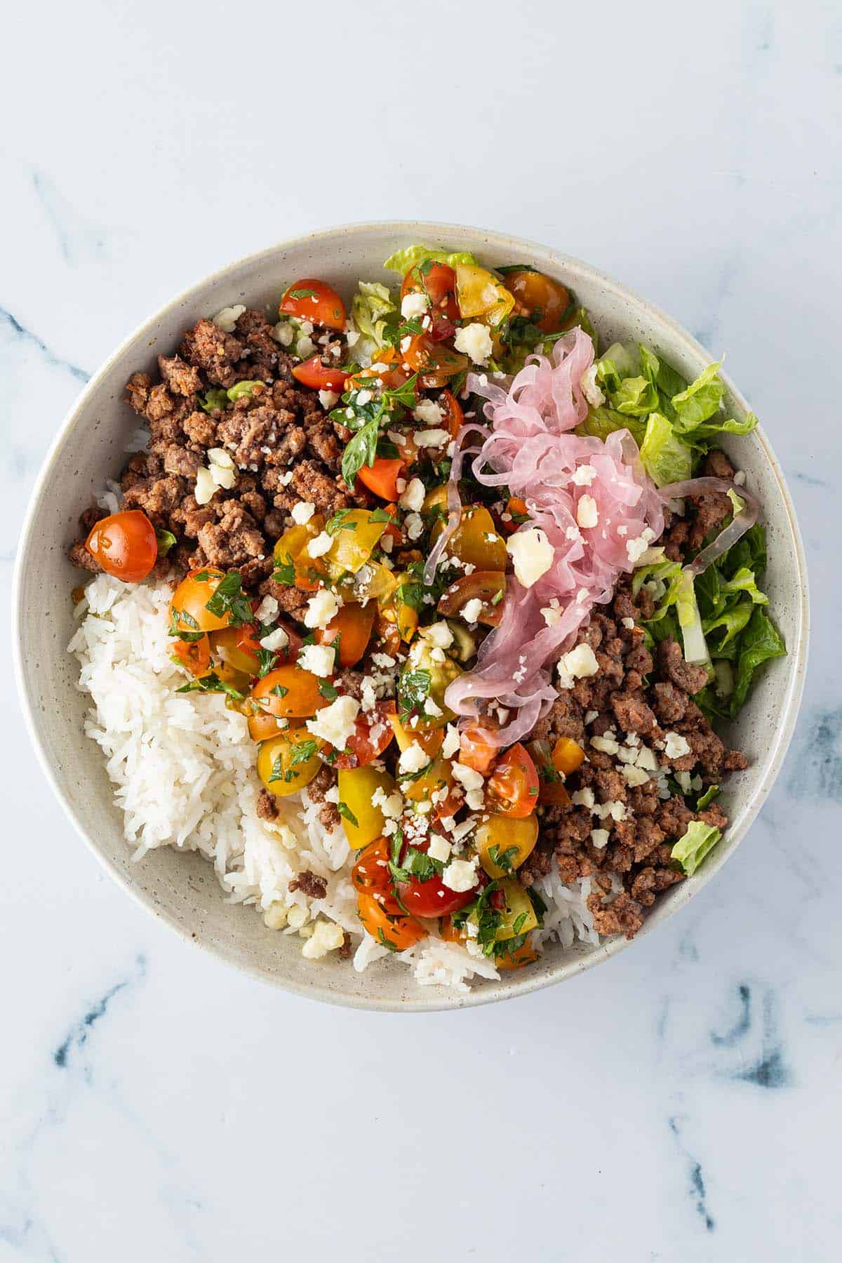 Taco Bowl mit Reis, Hackfleisch, Salat, Salsa und Pickled Onions.