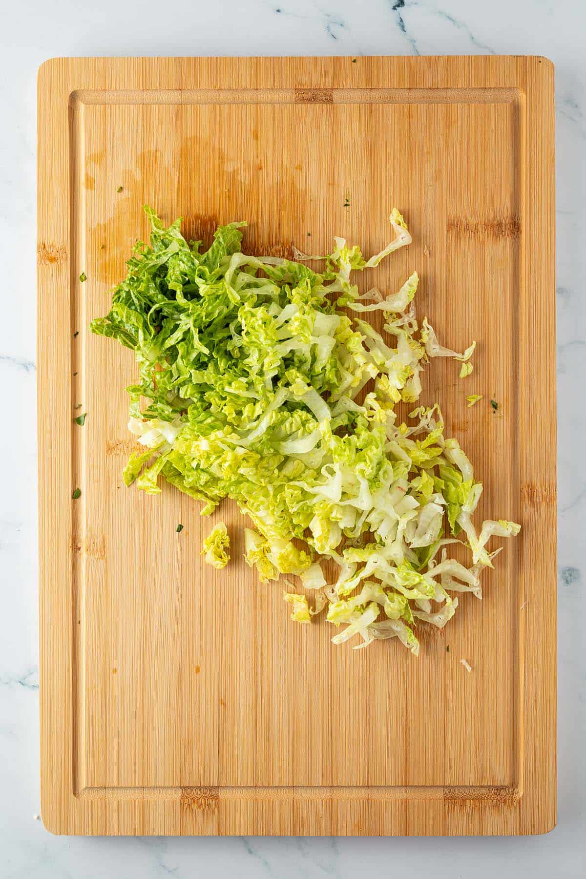 In d&uuml;nne Streifen geschnittener Salat auf einem Holzbrett.
