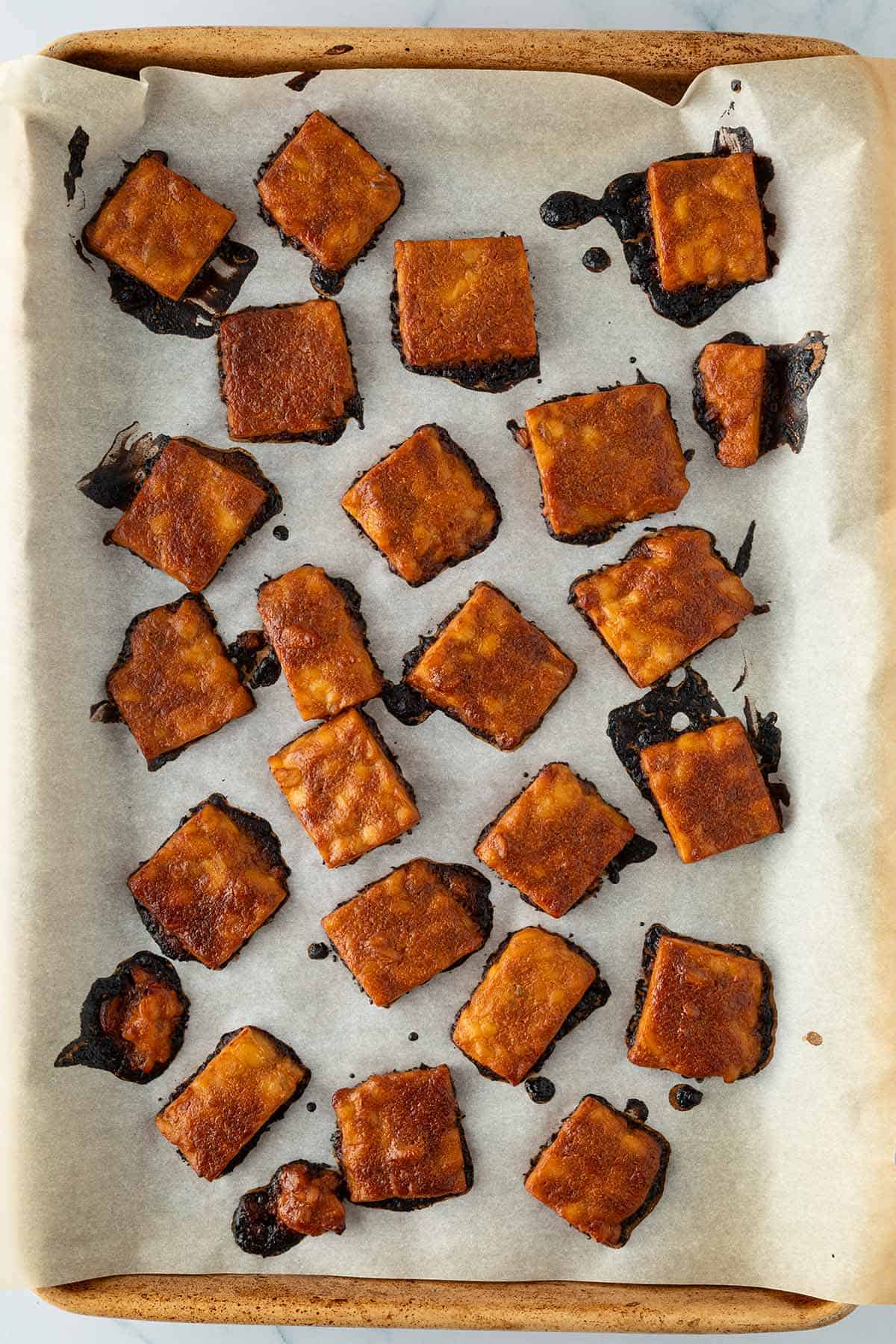 Gebackene Tempeh-St&uuml;cke auf einem Backblech.
