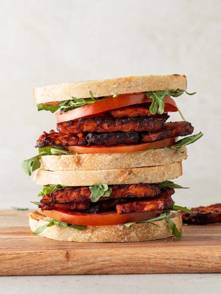 Zwei aufeinander gestapelte Tempeh Sandwiches mit Veganer Tempeh Bacon, Tomaten und Salat.