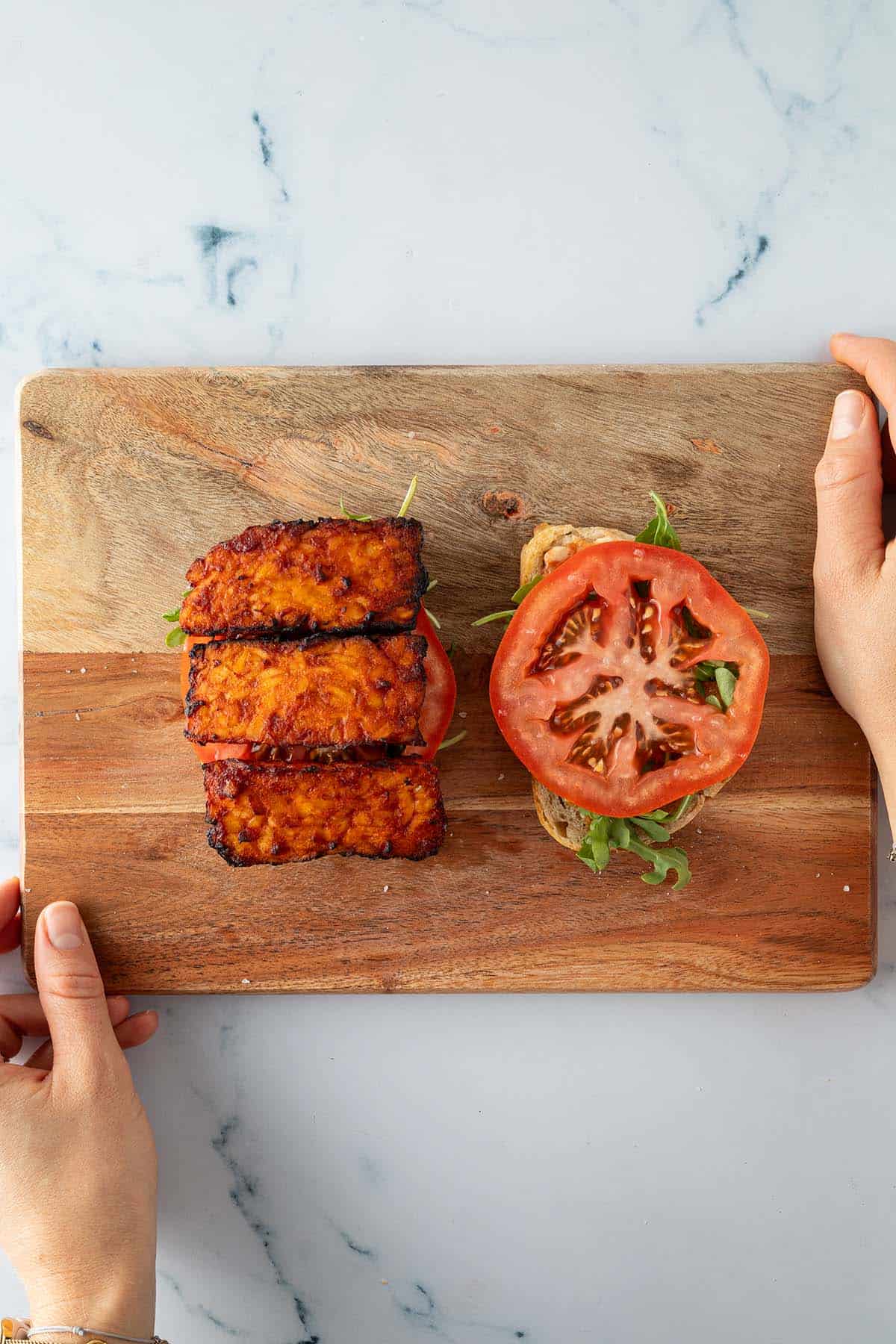 Zwei belegte Broth&auml;lften, eine mit Salat und Tomaten, die andere mit Tempeh Bacon Scheiben.