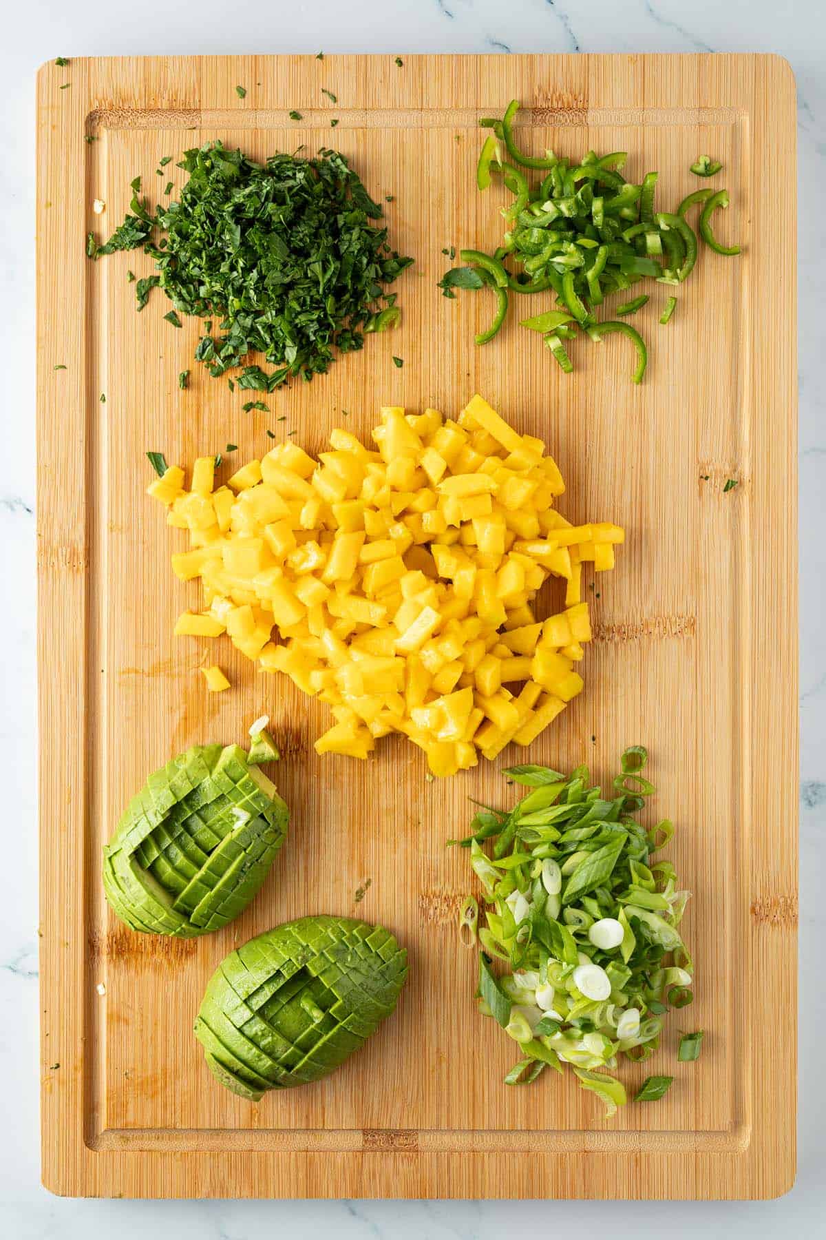 Geschnittenes Gem&uuml;se f&uuml;r die Mango Avocado Salsa auf einem Brett.