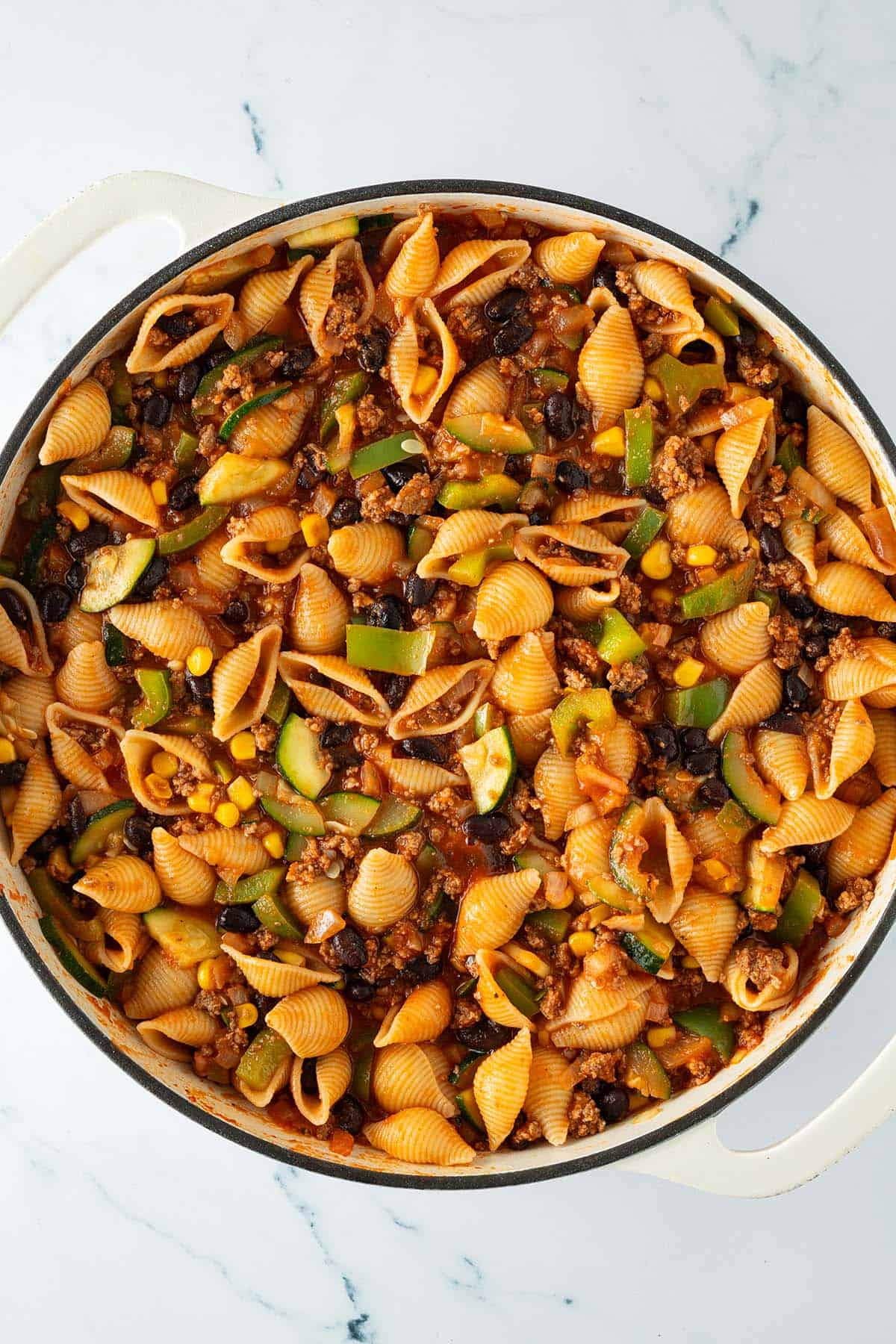 Gro&szlig;e Pfanne mit gekochten Muschelnudeln, Hackfleisch, Zucchini, Mais und schwarzen Bohnen in w&uuml;rziger Tomatensauce.