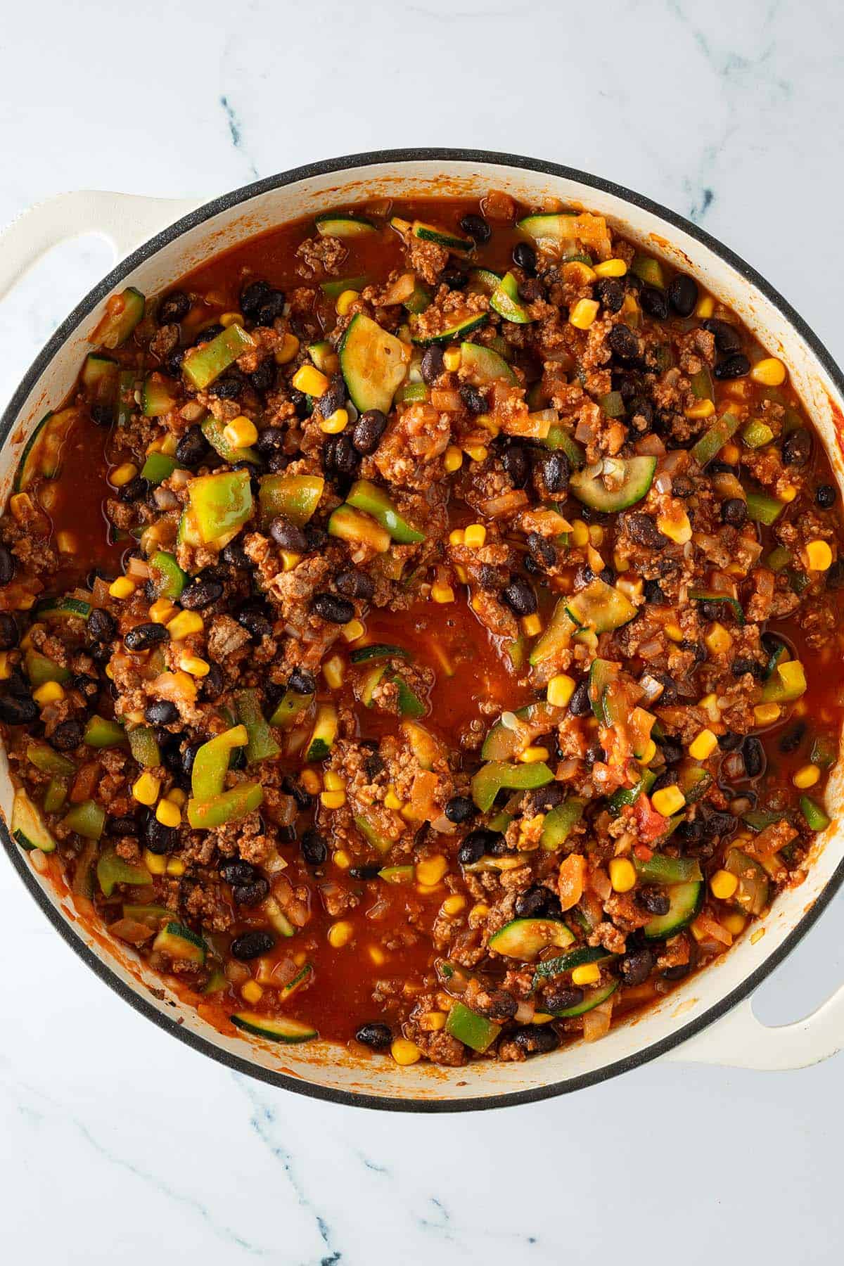 Pfanne mit k&ouml;chelnder Tex-Mex Hackfleisch-Gem&uuml;se-Sauce aus Zucchini, Paprika, Mais und schwarzen Bohnen in Tomatensauce.
