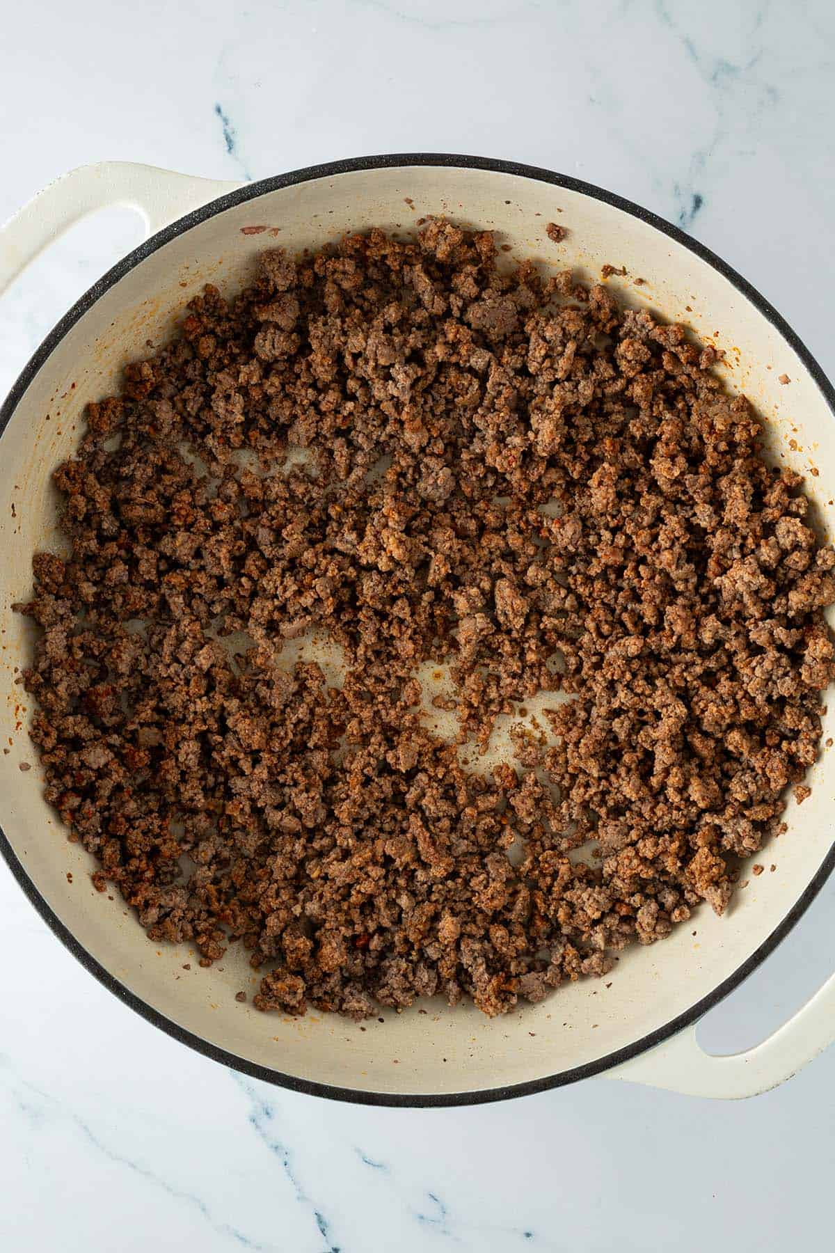 Pfanne mit kr&uuml;melig angebratenem Hackfleisch gleichm&auml;&szlig;ig verteilt &uuml;ber den Pfannenboden.