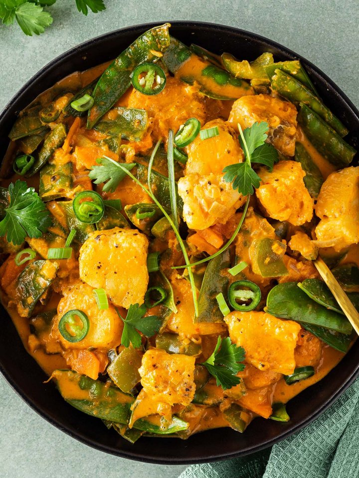 Thail&auml;ndisches Curry mit Frischst&uuml;ckchen, Gem&uuml;se und einer cremigen Sauce wird serviert mit frischen Kr&auml;utern.
