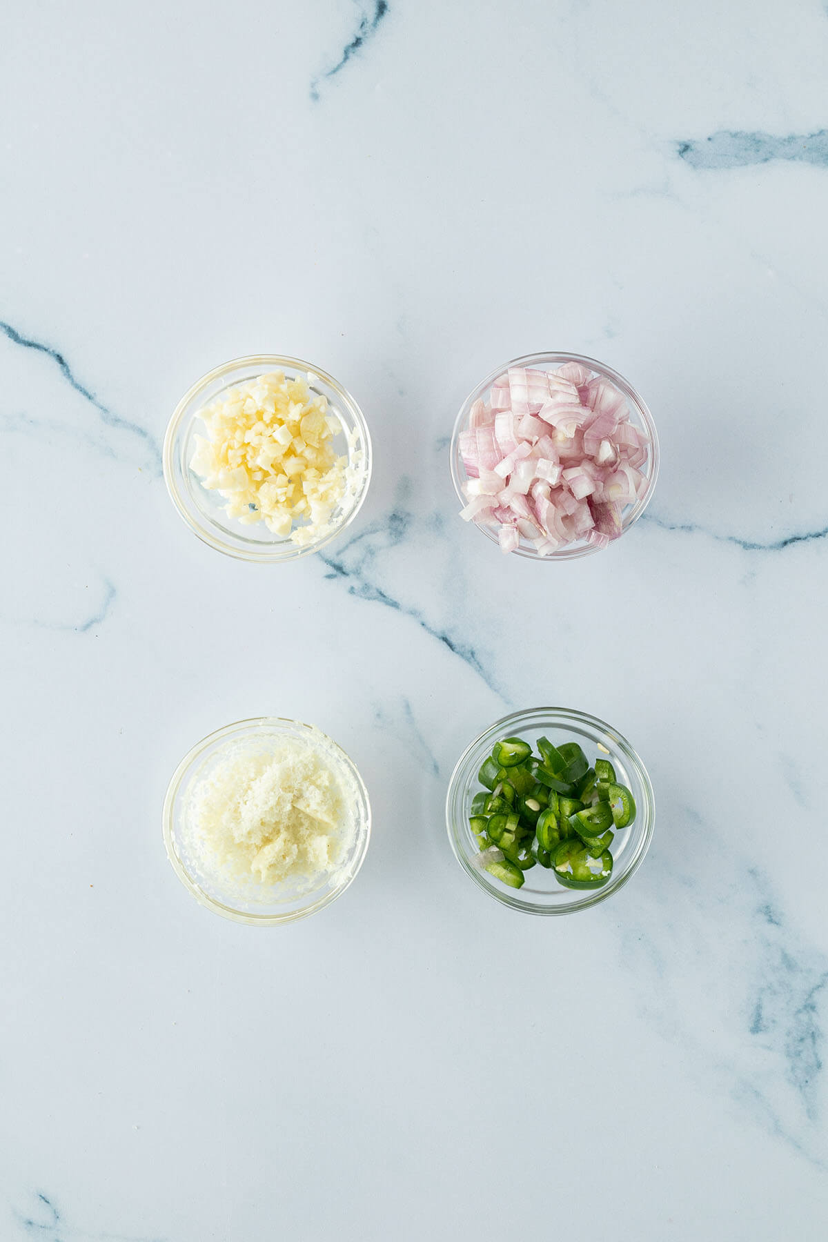 Vier kleine Sch&uuml;sseln mit fein gew&uuml;rfeltem Knoblauch, Schalotte, eine klein geschnittene Chili und geriebenen Ingwer.