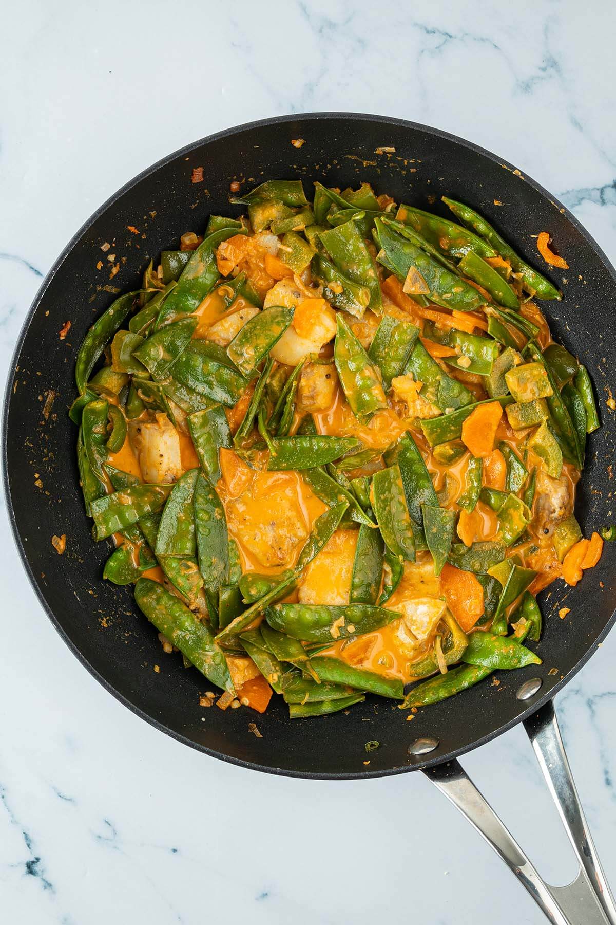 Vogelperspektive auf einen Wok mit einem Thai Curry mit Fisch und reichlich Gem&uuml;se.