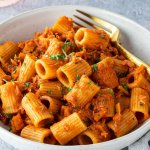 Ein Teller mit Rigatoni in einer Thunfisch-Toamtenso&szlig;e auf einem hellgrauen Untergrund.