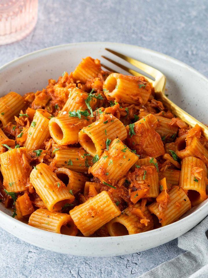 Ein Teller mit Rigatoni in einer Thunfisch-Toamtenso&szlig;e auf einem hellgrauen Untergrund.