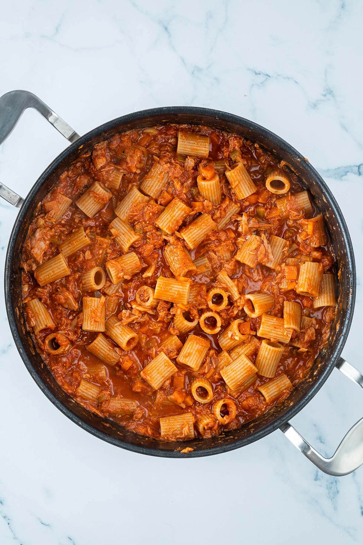 Rigatoni Nudeln in einer Tomaten Thunfisch Sauce serviert in einer gro&szlig;en Pfanne.