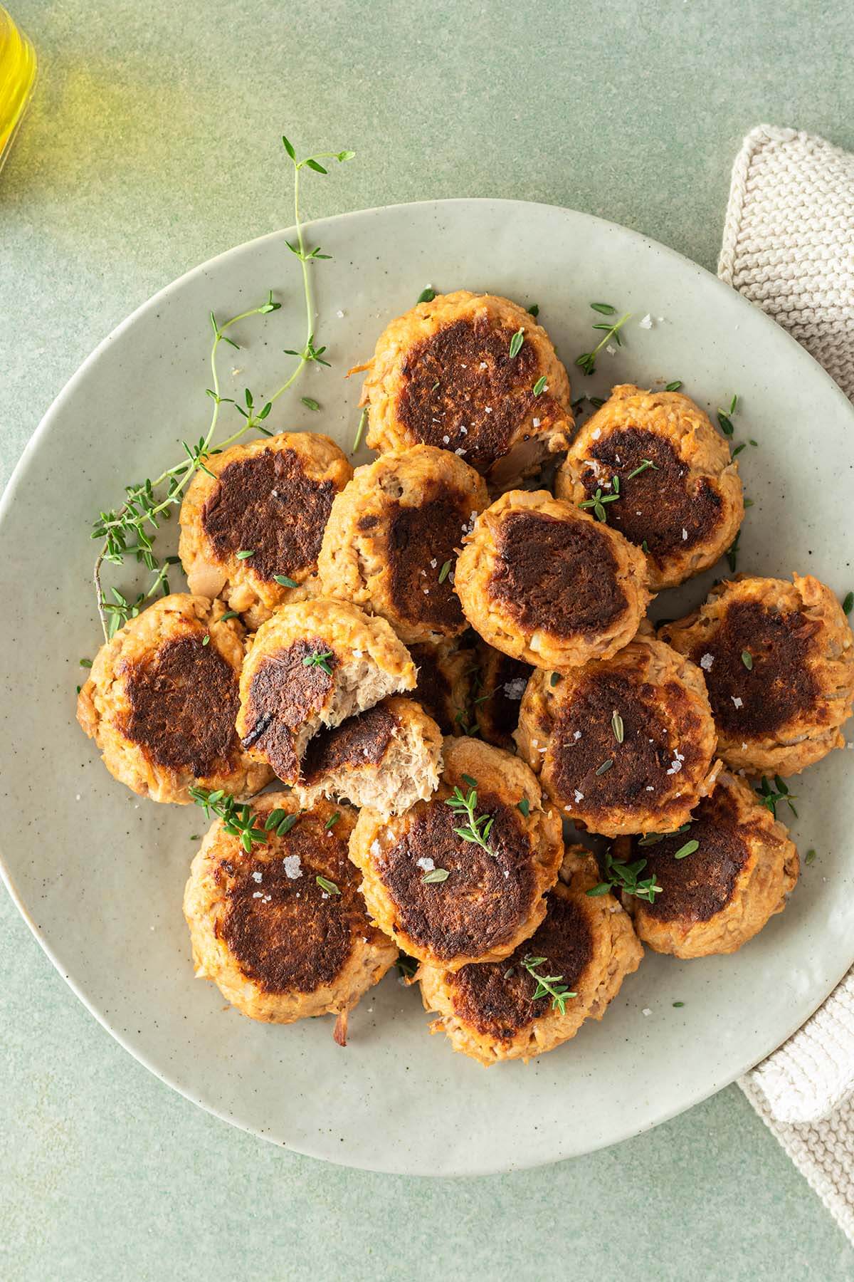 Viele, knusprig angebratene Thunfischb&auml;llchen auf einem Teller, mit Deko im Bildrand.
