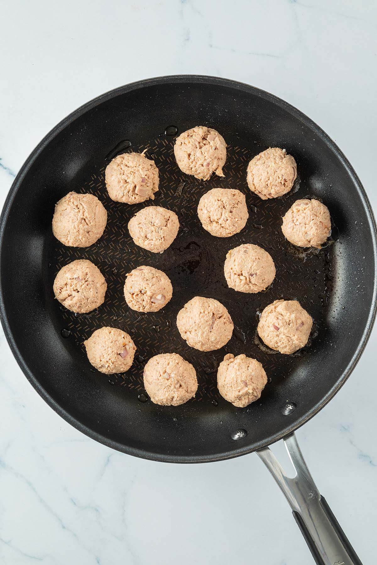 Kleine, runde Thunfischb&auml;llchen in einer Pfanne.