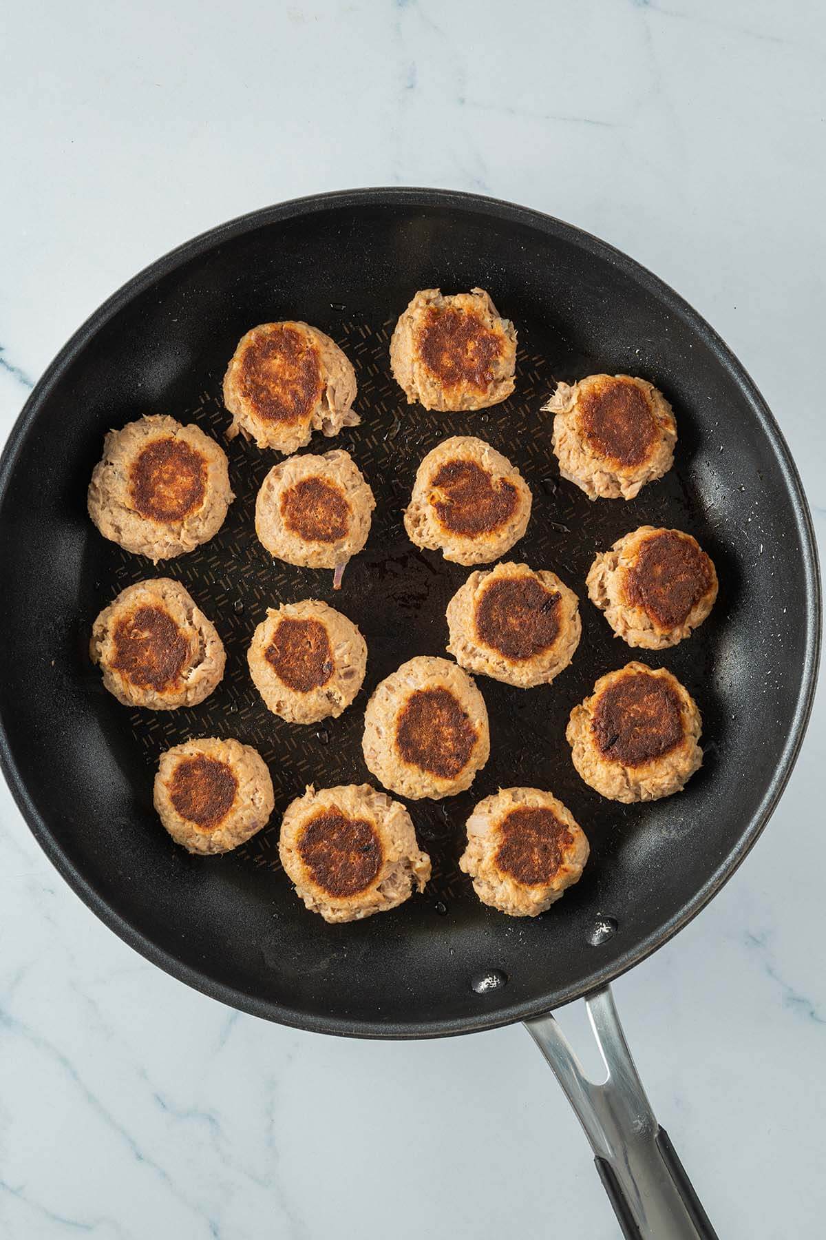 Knusprig angebratenen Thunfischb&auml;llchen in einer Pfanne.